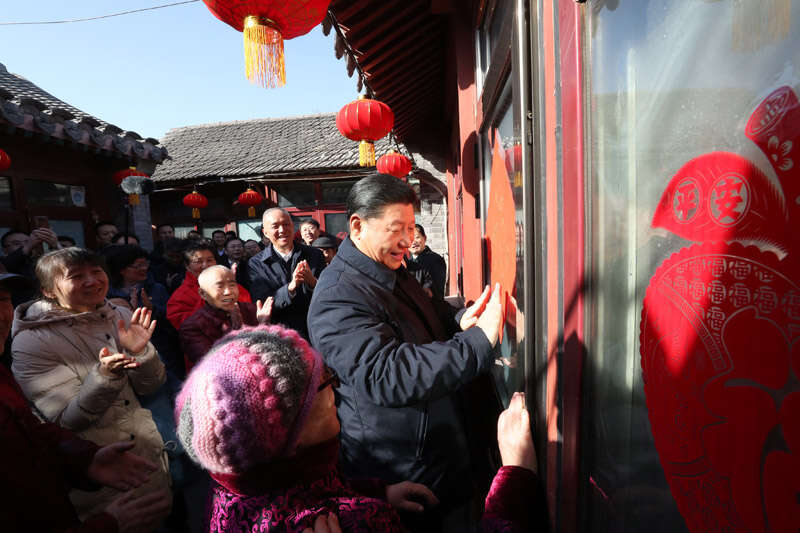 2019年2月1日上午，習近平在北京前門(mén)東區草廠(chǎng)四條胡同32號院，高興地拿起一幅“?！弊?，親自貼到門(mén)上，給這里的老街坊們拜年。新華社記者 鞠鵬 攝